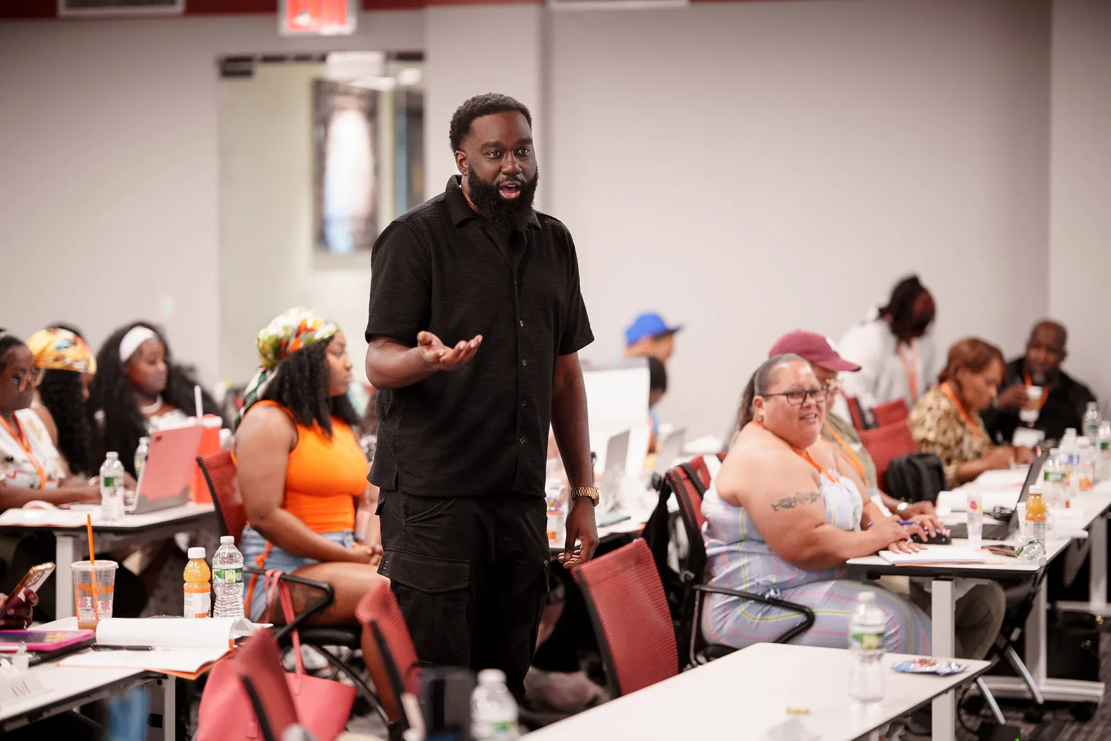 Coach Reem teaching a workshop with attendees working at tables
